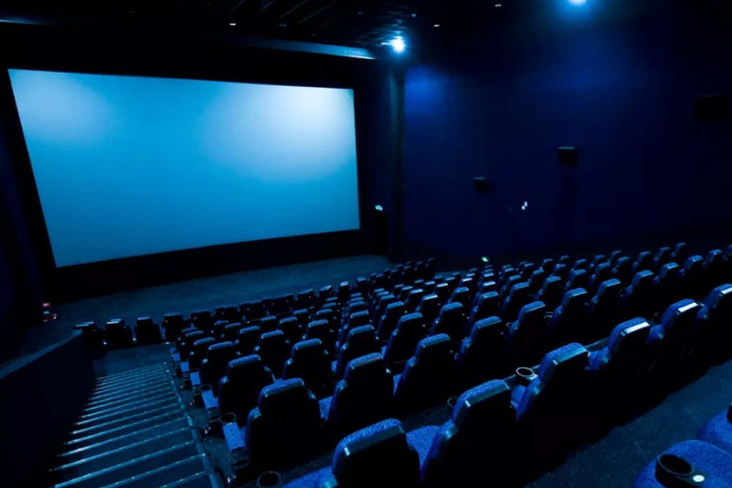 Picture of a movie theater with a blue light cascading over the seats and screen.